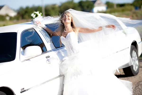 Jovem noiva de pé ao lado de uma limusine — Fotografia de Stock