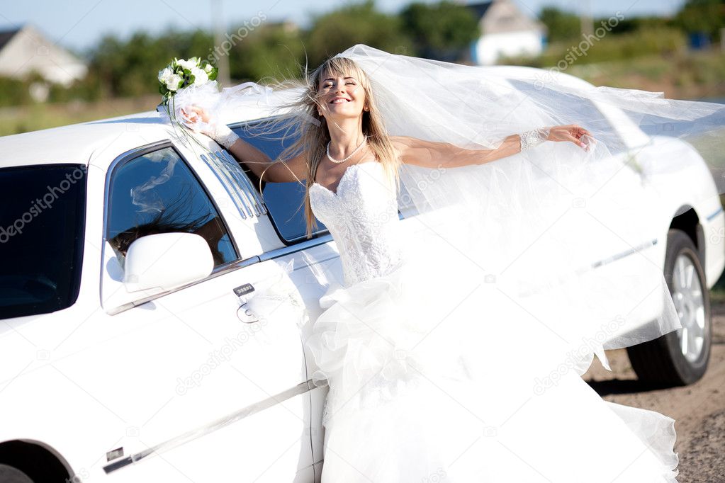 Young bride standing beside a limousine
