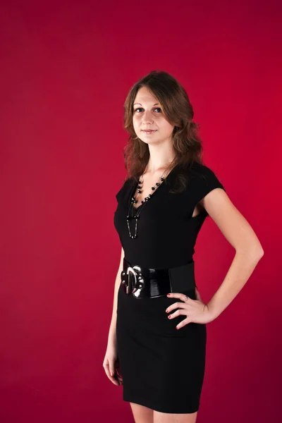 Flickan i svart klänning på en röd bakgrund — Stockfoto