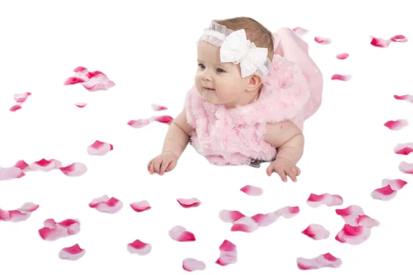 A cute baby girl lying on the ground covered in flower petals — Stock Photo, Image