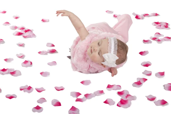 Egy aranyos baba lány feküdt a földön szereplő virágszirmok — Stock Fotó