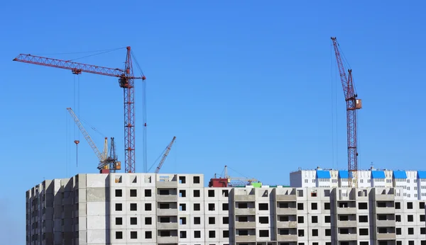 Kraan en blauwe hemel op de bouwplaats — Stockfoto