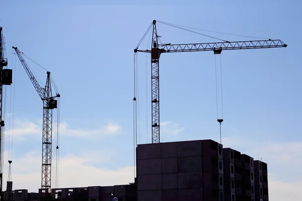 Kraan en blauwe hemel op de bouwplaats — Stockfoto