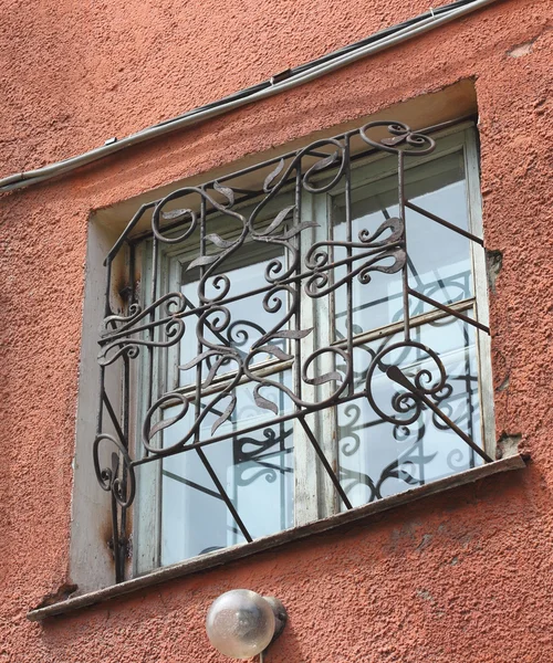 Metal forjado entalhado treliça em uma janela branca de plástico — Fotografia de Stock