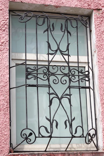 Rejilla tallada forjada de metal negro en una ventana blanca de plástico — Foto de Stock