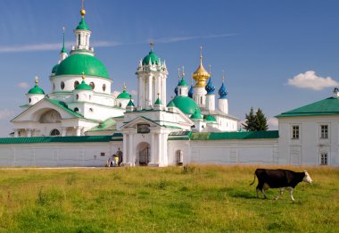 Cow goes past the Spaso-Yakovlevsky Monastery in Rostov clipart