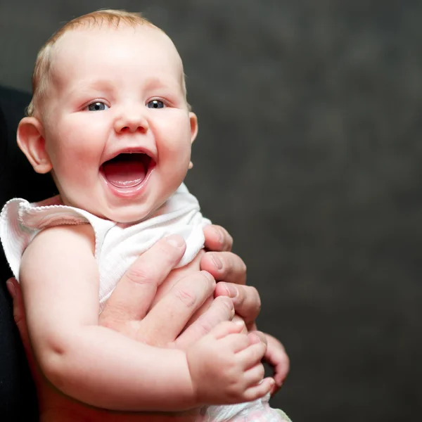 Um lindo bebê sorridente nas mãos de seu pai — Fotografia de Stock