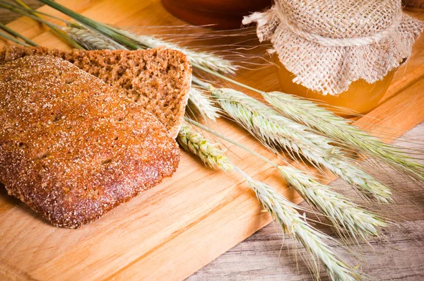Φέτες ψωμί και σιτάρι στο ξύλινο τραπέζι — Φωτογραφία Αρχείου