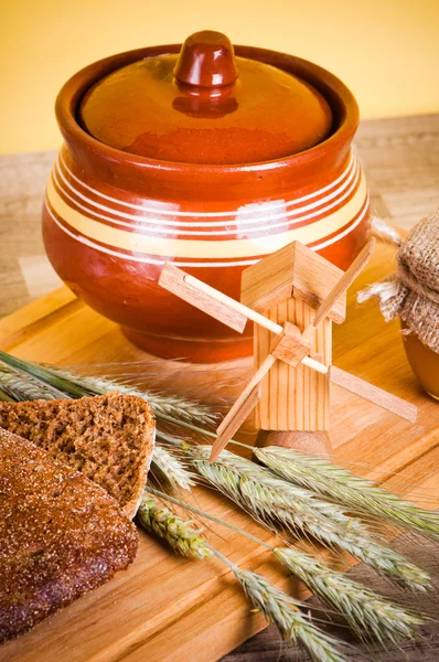 Φέτες ψωμί και σιτάρι στο ξύλινο τραπέζι — Φωτογραφία Αρχείου