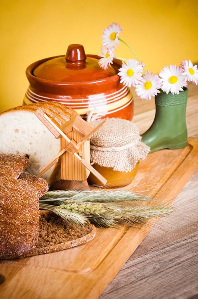 Нарезанный хлеб и пшеница на деревянном столе — стоковое фото