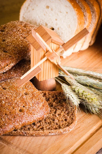 Sliced bread and wheat on the wooden table — Stock Photo, Image