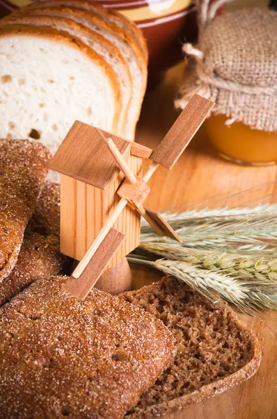 Plátky chleba a pšenice na dřevěný stůl — Stock fotografie