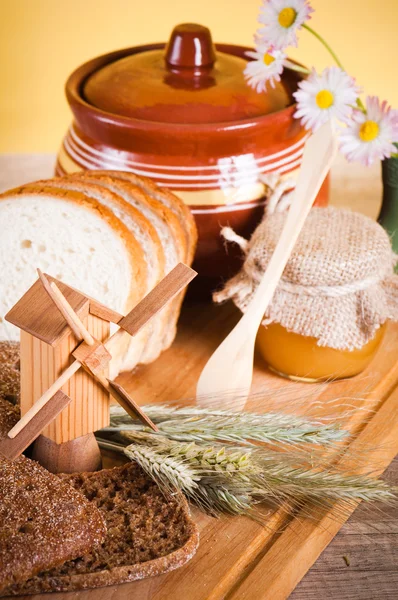 Honey, flowers, spike and bread on table — Stock Photo, Image