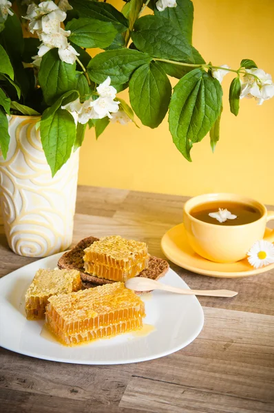 Honeycomb with a cup of tea and a bouquet of blooming Jasmine — Stock Photo, Image