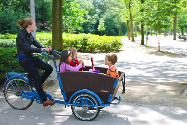 Jovem transportando crianças no carrinho. Amesterdão. Mais baixo. Imagem De Stock