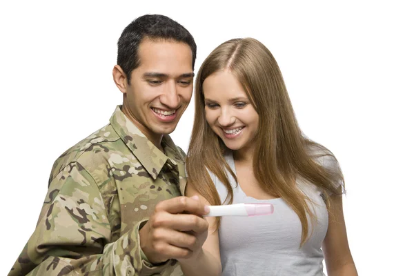 軍の男性と彼の妻の妊娠検査で笑顔します。 ストックフォト