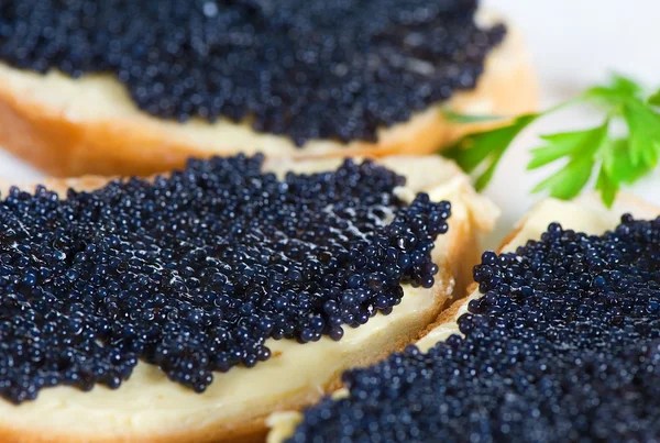 Black caviar on a slice of bread and butter — Stock Photo, Image