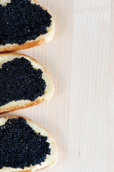 Black caviar on a slice of bread and butter — Stock Photo, Image