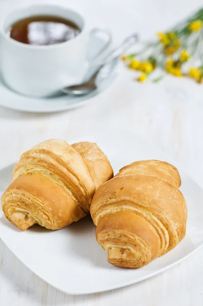 Croissants mit einer Tasse Tee — Stockfoto
