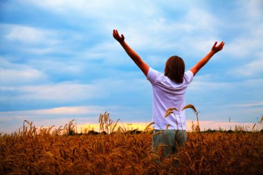 Young man staying with raised hands at sunset time clipart