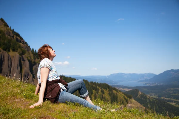 Kvinna sitter på toppen av en klippa — Stockfoto