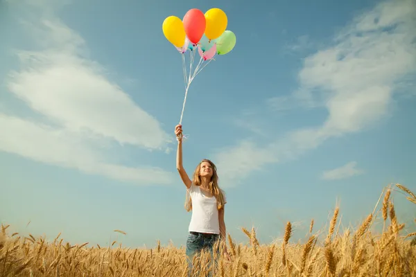 Девушка-подросток на пшеничном поле с воздушными шарами — стоковое фото