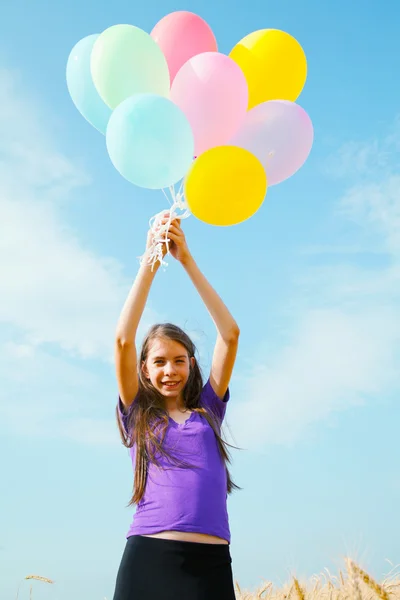 Девушка-подросток на пшеничном поле с воздушными шарами — стоковое фото