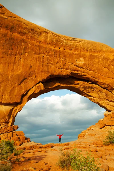 Женщина, стоящая с поднятыми руками внутри арки — стоковое фото