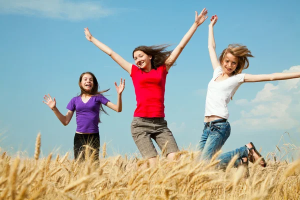 Teen girls jumping at a wheat field — Stock Photo, Image