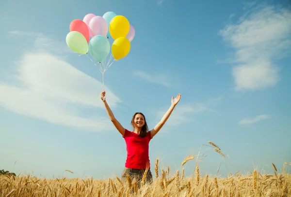 Tiener meisje op een tarweveld met kleurrijke ballonnen — Stockfoto