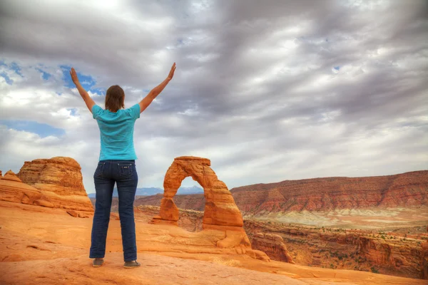 Mujer con las manos levantadas frente al Delicado Arco —  Fotos de Stock