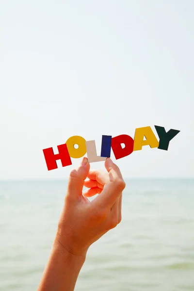 La mano de la mujer sosteniendo la palabra colorida 'Vacaciones' —  Fotos de Stock