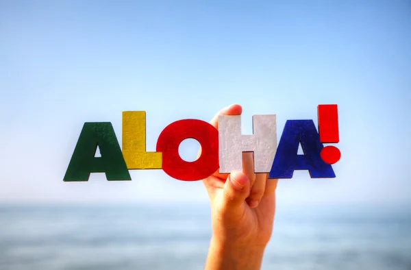 La mano de la hembra sosteniendo la palabra colorida 'Aloha' —  Fotos de Stock