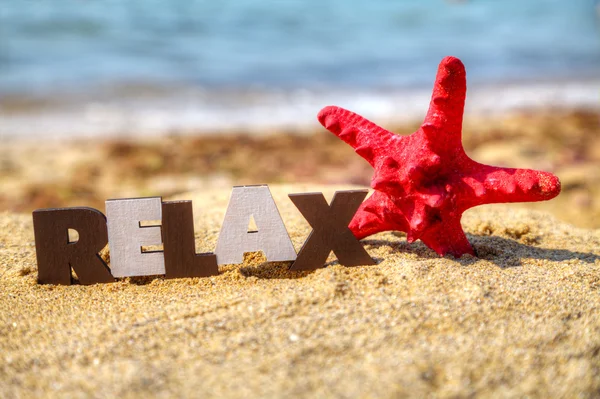 Houten woord 'ontspannen' met rode starfish — Stockfoto