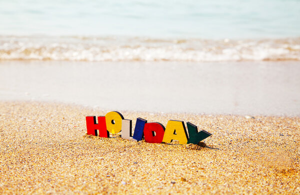 Wooden colorful word 'Holiday' on the sand