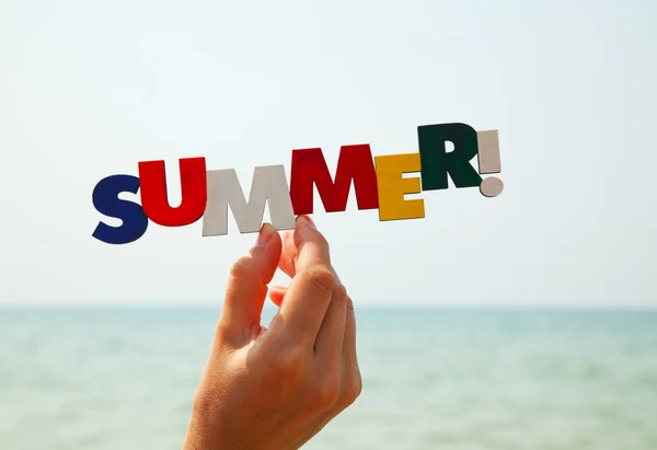 Vrouwelijke is hand bedrijf kleurrijke woord "zomer" — Stockfoto