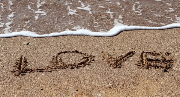 Le mot "amour" écrit sur le sable d'une plage . — Photo