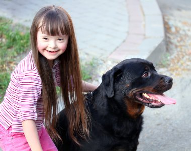 küçük kız ile büyük bir siyah köpek gülümsüyor