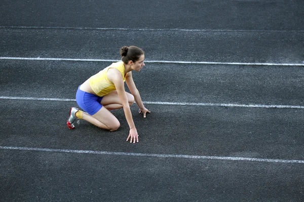 Sportovní dospívající dívka v počáteční pozici na trati . — Stock fotografie