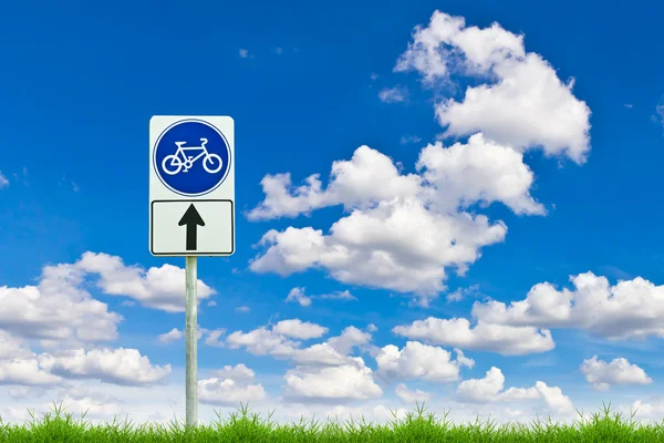 Señal de bicicleta camino en la hierba verde primavera fresca contra el cielo azul —  Fotos de Stock
