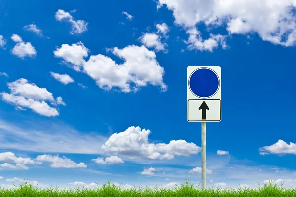 Blue blank sign on fresh spring green grass against blue sky — стоковое фото