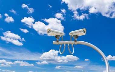 Surveillance cameras against blue sky clipart