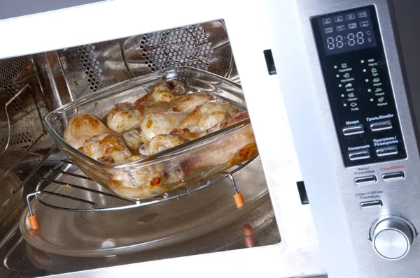 Куриные ножки на стеклянной тарелке в конвекционной печи — стоковое фото