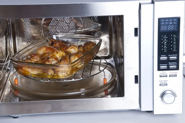 Kip benen op een schotel glas in de convectie oven — Stockfoto