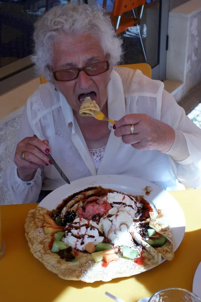 A senior lady eating a crepe — Stock Photo, Image