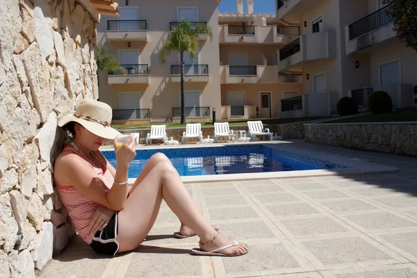 Uma jovem sentada à beira da piscina — Fotografia de Stock