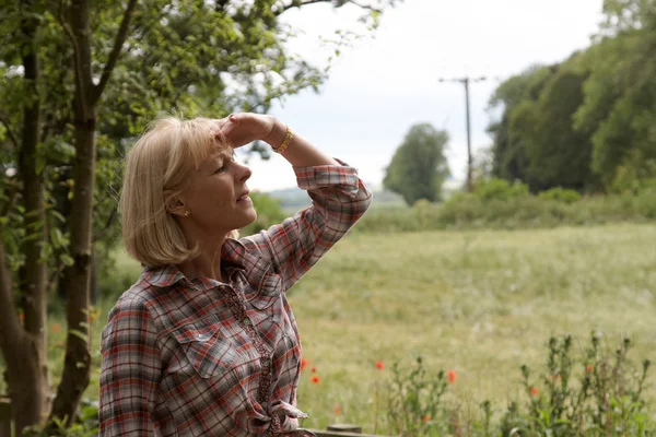 Uma mulher madura olhando sobre os campos — Fotografia de Stock