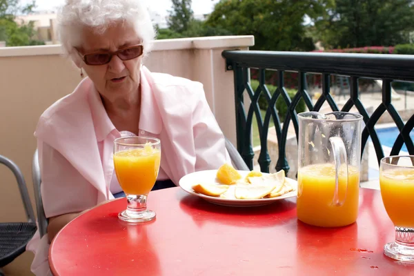 Una mujer mayor con jugo de naranja fresco —  Fotos de Stock