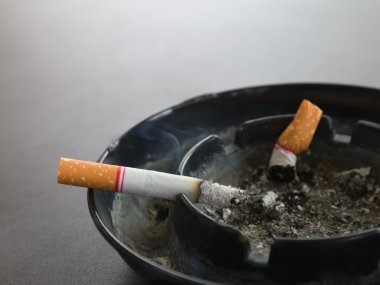 Masanın üzerinde duman ve kül tablası içinde sigara yakma portre