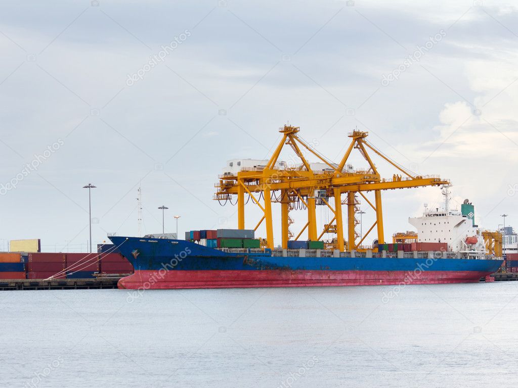 Port of container cargo freight ship with working crane bridge